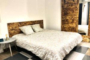 a bedroom with a bed with a wooden headboard and a table at Studio cocooning Spa, lit XXL, cour extérieure in Le Puy en Velay