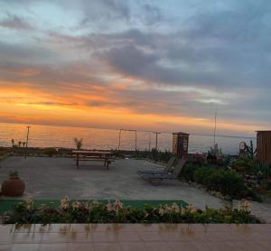 a sunset over the ocean with a picnic table and bench at Anastasia Apartment in Ayia Marina