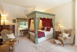 een slaapkamer met een hemelbed en 2 stoelen bij Flitwick Manor Hotel, BW Premier Collection in Flitwick