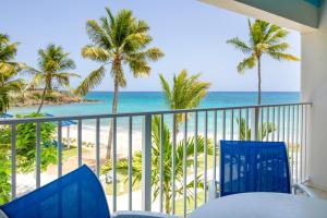 Limetree Beach Resort by Club Wyndham في Raphune: شرفة مطلة على الشاطئ والنخيل