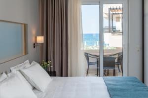 a hotel room with a bed and a view of the ocean at Corinna Mare in Kalamaki +105 photos