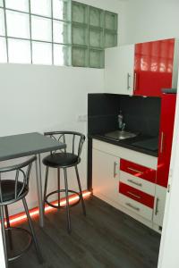 リューネブルクにあるAppartement-an-der-Ilmenauのキッチン(椅子2脚、テーブル、赤いキャビネット付)