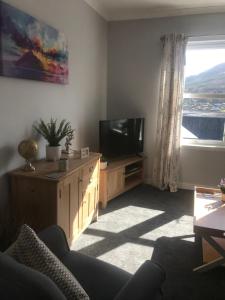 a living room with a tv and a couch and a window at 4 York Drive, Portree , Isle Of Skye in Portree