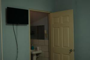 a bathroom with a television on the wall next to a door at Hotel Valerie in Managua