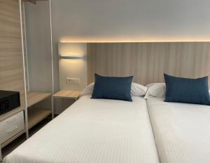 2 camas con almohadas azules en una habitación de hotel en LC Hotel Urbano, en Alicante