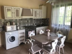 a kitchen with a table and a stove and a washing machine at Val Giardino Vintage Cottage in Roccamorice