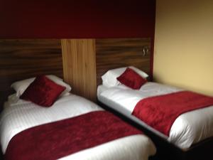 
two beds in a hotel room with red pillows at Mourne Country Hotel in Newry
