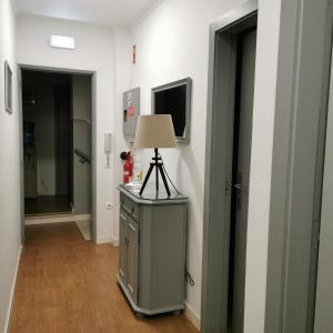 a hallway with a lamp on a dresser and two doors at Flor da Primavera - Residencial e Apartamentos in Azambuja