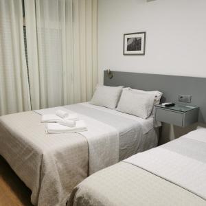 Dos camas en una habitación de hotel con toallas. en Flor da Primavera - Residencial e Apartamentos en Azambuja
