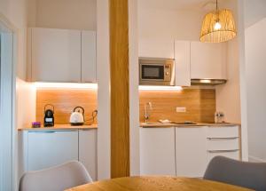 cocina con armarios blancos, mesa y microondas en CosyBNB bleu, logement indépendant, wifi, parking, petit déjeuner, en Ittenheim