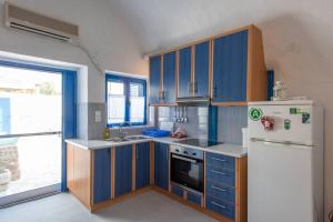 a kitchen with blue cabinets and a white refrigerator at Eva's Guesthouse in Éxo Goniá +11 photos