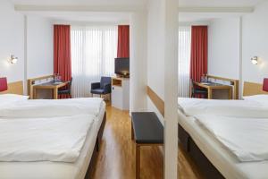 a hotel room with two beds and a desk at Swiss Star Irchel - Self Check-In in Zurich