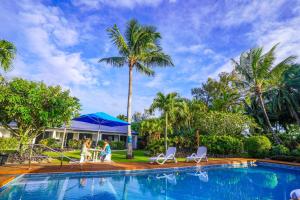 una familia caminando junto a una piscina con palmeras en The Black Pearl Beachside Apartments en Rarotonga
