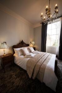 a bedroom with a large bed and a chandelier at East Walls Hotel in Chichester