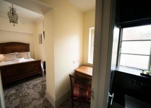 a bedroom with a bed and a desk and a window at East Walls Hotel in Chichester