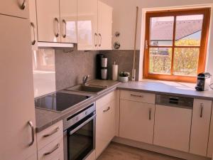 cocina con armarios blancos, fregadero y ventana en Ferienwohnung Hörnerblick, en Sonthofen