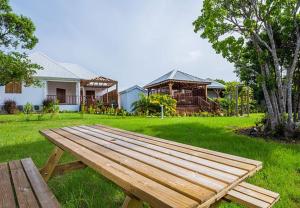 a wooden picnic table in a yard with a house at Maison cosy avec jardin à Anse-Bertrand in Anse-Bertrand