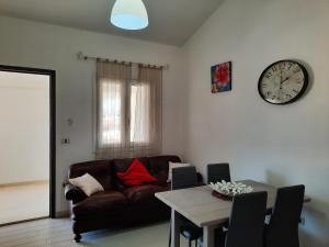 ein Wohnzimmer mit einem Sofa, einem Tisch und einer Uhr in der Unterkunft Casa Elias in Orosei