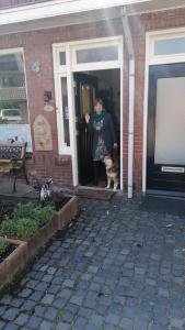 una mujer parada en la puerta de una casa con un gato en B&B Bij de koeien, en Tubbergen