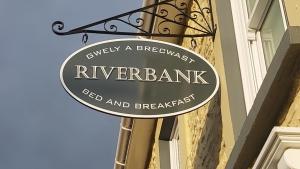 una señal para una orilla del río a un lado de un edificio en Riverbank Bed and Breakfast, en Llanwrtyd Wells