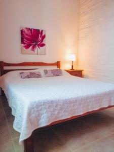 a bedroom with a white bed with a pink flower on the wall at Las Casuarinas in Piriápolis