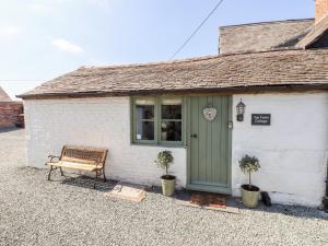 a building with a bench and a green door at Top Farm Cottage in Oswestry