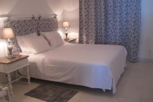 een slaapkamer met een wit bed met 2 tafels en 2 lampen bij Casa do Cais in Calheta