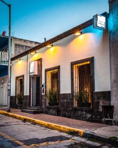 un bâtiment blanc avec des fenêtres et des plantes dans une rue dans l'établissement Hoteles ANTIGUA - SANTA LUCIA MTY, à Monterrey