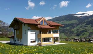 ein Haus auf einem Feld mit Bergen im Hintergrund in der Unterkunft ANDREA in Fügen