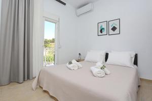 a white bedroom with a bed with towels on it at Mare Monte Luxury Apartments 2 in Nea Skioni
