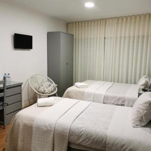 Pokój hotelowy z 2 łóżkami i krzesłem w obiekcie Flor da Primavera - Residencial e Apartamentos w mieście Azambuja