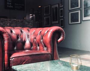 a red leather couch sitting in a room with a table at Hotel Hvolsvollur - Central South Iceland in Hvolsvöllur