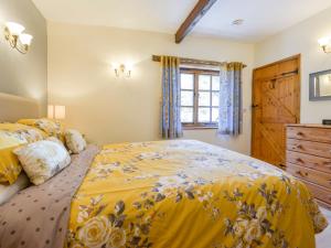 a bedroom with a yellow bed and a window at Miners Dry in Gunnislake