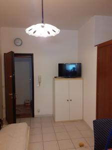 a living room with a television and a chandelier at condominio guanabara in Lido di Jesolo