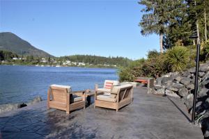 two chairs and a table next to a body of water at Private Oceanfront Cabin With Hot Tub Doc Holiday Cabin in Ucluelet +21 photos