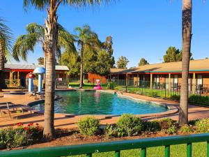 a swimming pool in front of a building with palm trees at Barooga Country Inn Motel in Barooga