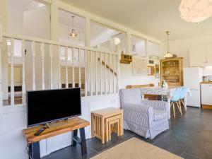 sala de estar con TV de pantalla plana y mesa en 2 Brook Cottages, en Hope-Cove