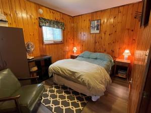 een slaapkamer met een bed en een stoel erin bij Grandpa Jim's Cabin in Montreal