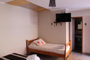 Habitación pequeña con cama y TV de pantalla plana. en Vicuña Lodge, en San Pedro de Atacama