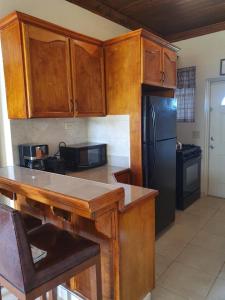 a kitchen with wooden cabinets and a black refrigerator at Fishtails Palms - Tamarind in Stuart Manor