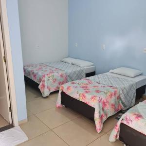 a room with three beds with covers on them at Pousada Cachoeiras do Jalapão in São Félix do Tocantins