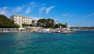 a dock in the water next to a large building at Hôtel Belles Rives in Juan-les-Pins