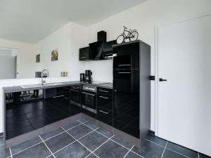 een keuken met zwarte kasten en een wastafel bij Beautiful house in Flemish Ardennes for cyclists in Ronse