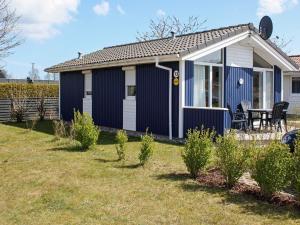 a blue cottage with a table and chairs in a yard at 4 person holiday home in GROEMITZ in Grömitz