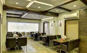 un restaurante con mesas y sillas y una gran ventana en Hotel Aaram Orchard, en Ahmedabad
