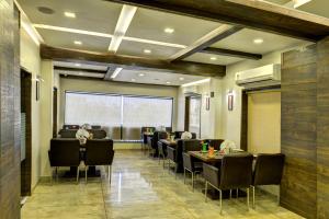 un restaurante con mesas y sillas negras y una gran ventana en Hotel Aaram Orchard, en Ahmedabad