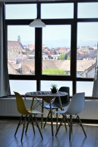 uma mesa e cadeiras num quarto com uma grande janela em Panorama studio em Sibiu