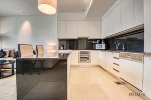 a kitchen with white cabinets and a black counter top at Exquisite 1BR at The Address Residences Dubai Marina by Deluxe Holiday Homes in Dubai