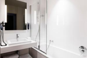 a white bathroom with a sink and a shower at Hôtel Le Windsor Biarritz in Biarritz