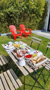 a picnic table with food on it with two red chairs at Au gré des vents in Saint-Quay-Portrieux